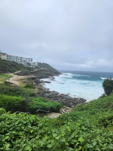 Turquoise waves crashing against the cliffs and green foliage.