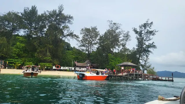 Boats moored at the pier of Mamutik Island under a tropical sun.