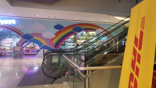 A colorful rainbow mural near the escalators of a shopping mall toy store.