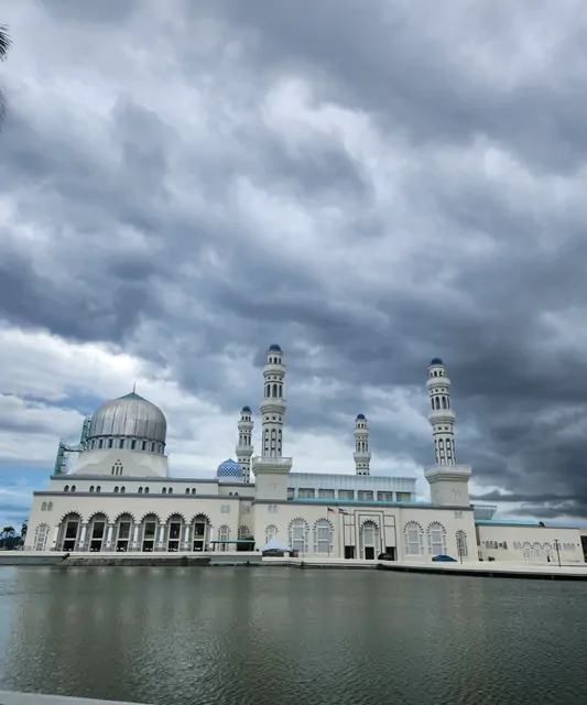 The blue dome of the City Mosque against a heavy, pre-rain grey sky.