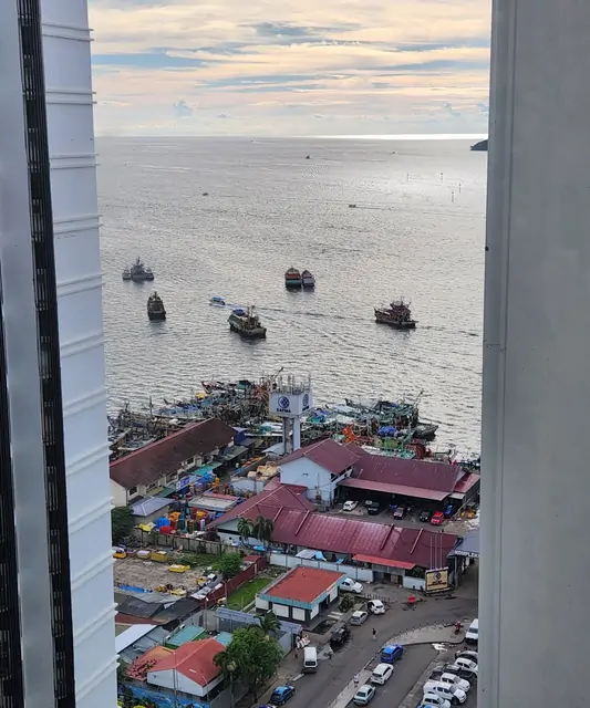 A glimpse of the fish market and harbor through a gap between buildings.