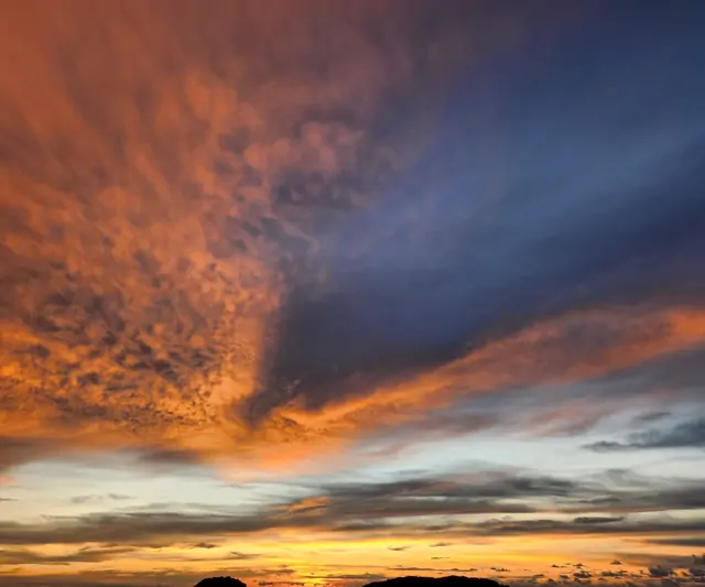 Dramatic red and navy clouds over the silhouette of the mountains at sunset.