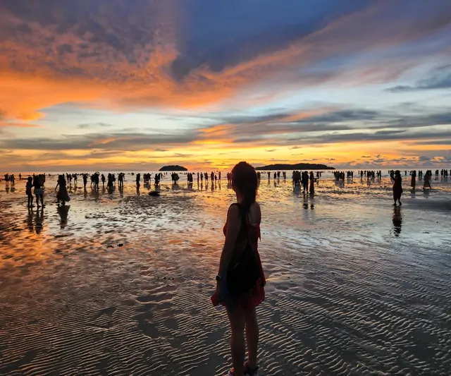 Silhouettes of people watching the final glow of the sunset on the beach.