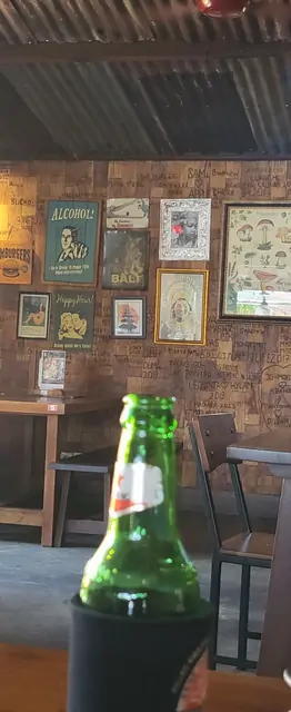 Vintage posters and a beer bottle in a rustic Bali bar.