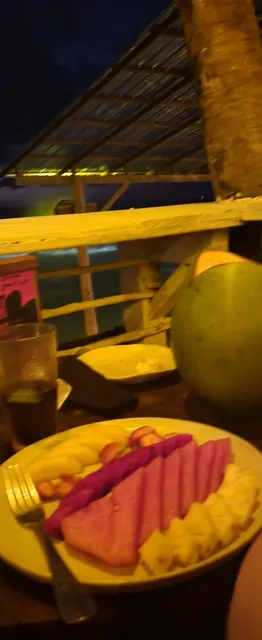 A platter of watermelon and pineapple at an outdoor beach bar at night.