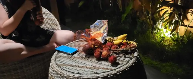 A night snack of rambutan and bananas on an outdoor table.