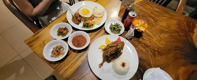 Traditional Indonesian nasi goreng and roasted duck on a wooden table.