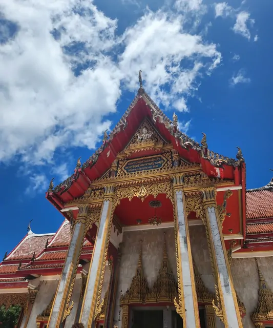 The red and gold decorative roof of a temple against a blue sky.