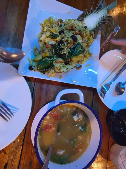 Pineapple fried rice and vegetable soup served on a wooden table.