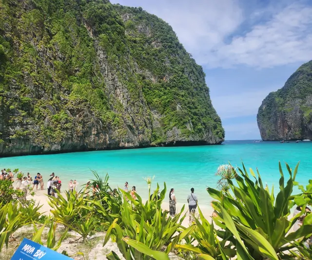 Tourists enjoying the emerald waters and cliffs of Maya Bay.
