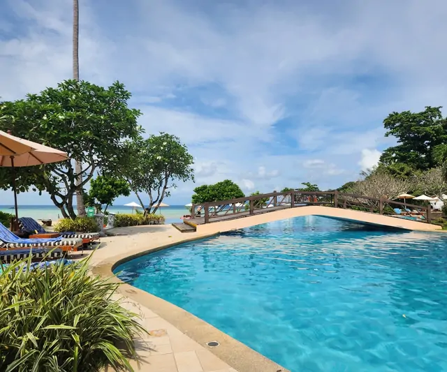 A resort swimming pool overlooking the blue ocean.