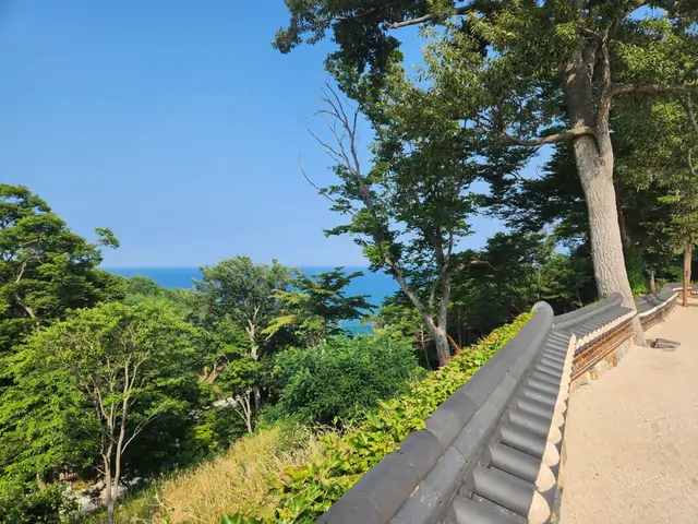 Stone railings on a hill overlooking the summer ocean.