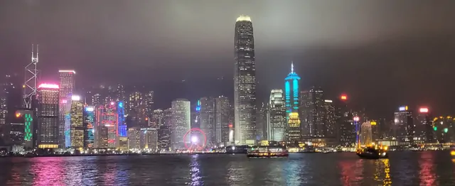 The illuminated IFC building and the harbor skyline at night.