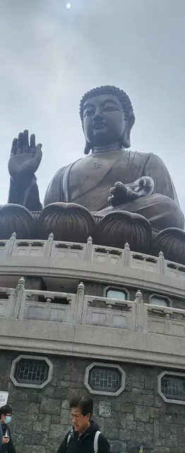 A visitor walking toward the Great Buddha on a cloudy day.