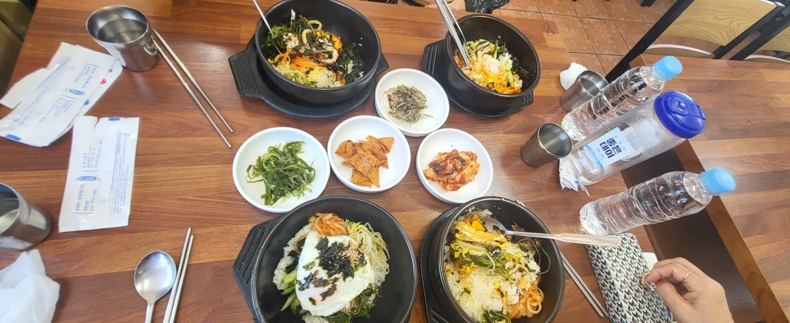 A hearty table of dolsot bibimbap and various side dishes at a Korean restaurant.