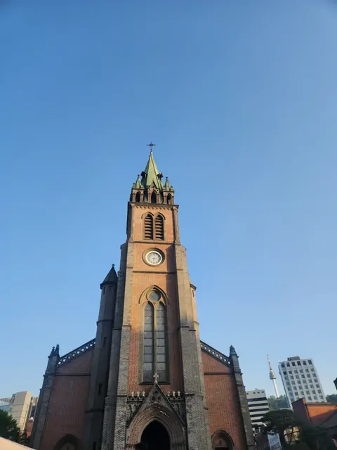 青空を背景に高く伸びる、明洞聖堂の赤いレンガの尖塔