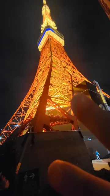 A low-angle view looking up at the glowing Tokyo Tower.