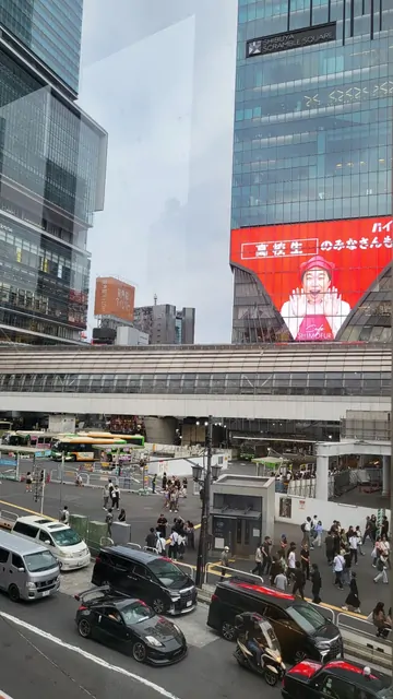 City traffic and large LED screens at a busy urban intersection.