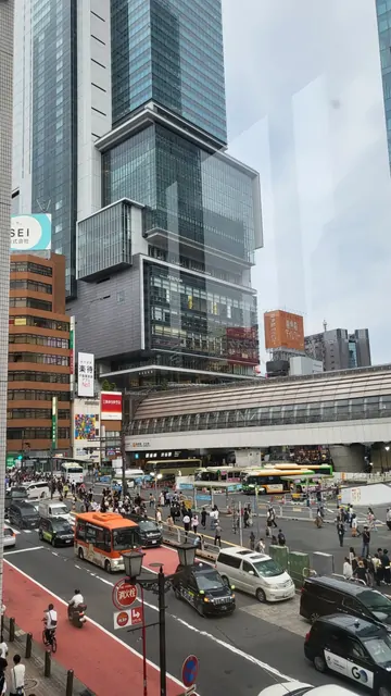 Buses and cars moving through the bustling streets of Shibuya.