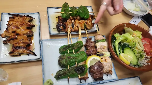 Yakitori skewers, peppers, and salad for an izakaya dinner.