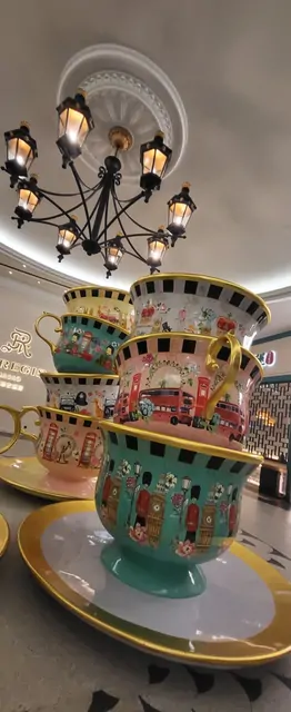 A large tea cup sculpture and chandeliers in the London-themed St. Regis lobby.