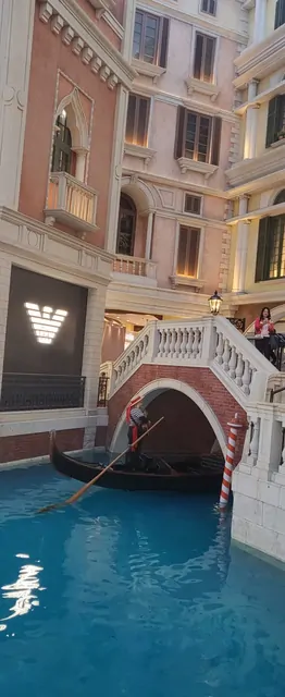 A gondola passing under an arched bridge in the Venetian indoor canal.