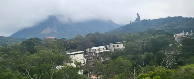 The Tian Tan Buddha standing amidst the misty ridges of Lantau Island.