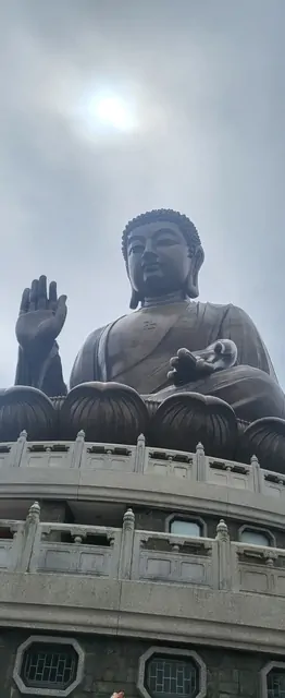 The massive bronze Tian Tan Buddha towering against a cloudy sky.