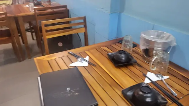 The blue interior and wooden table setting of an Asian restaurant.