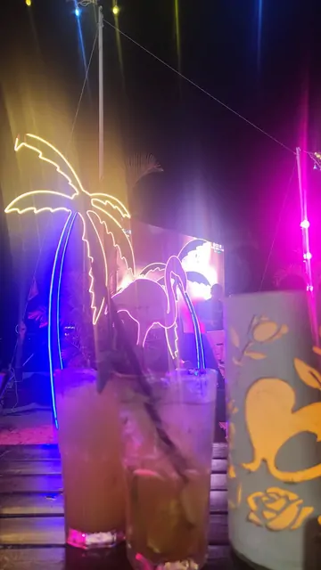 Neon palm trees and flamingo lights at a rooftop bar.
