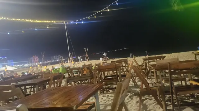 Outdoor seating with bulb lighting on the sandy beach at night.