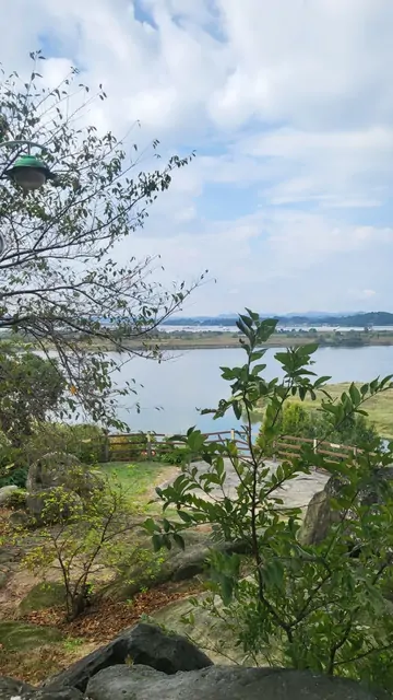 Wide river views framed by rocks and trees under a cloudy sky.