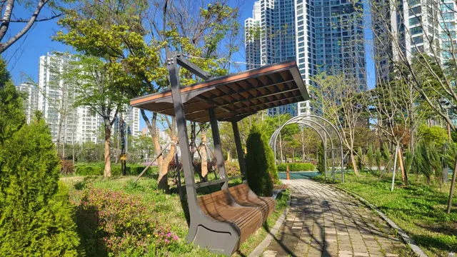Spring walking path and wooden pergola in a city park near apartments.