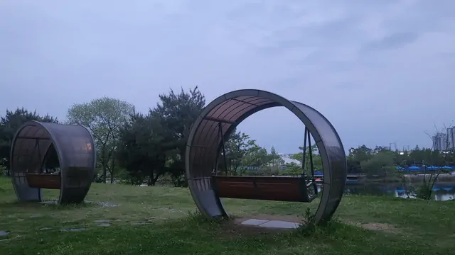 Circular sculpture bench on a grassy lawn during a cloudy evening.