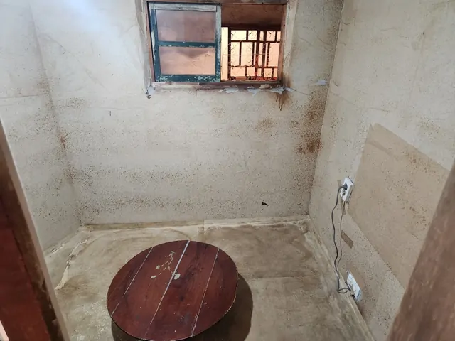 An empty, weathered room with a round wooden table in an old building.