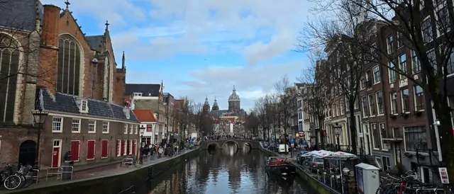 Winter view of Amsterdam canals lined with red brick buildings and a church dome.