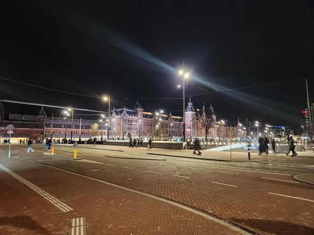 The illuminated architecture of Amsterdam Central Station at night.