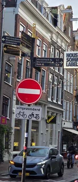 A dense cluster of traffic and bicycle signs at a city intersection.