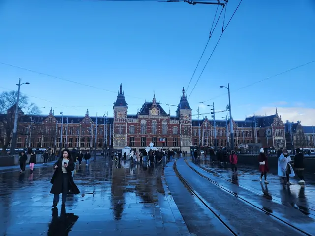 People crossing the damp square in front of Central Station on a winter evening.