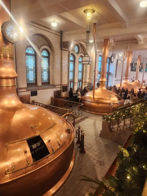 Massive copper fermentation vats and stained glass at the Heineken brewery.