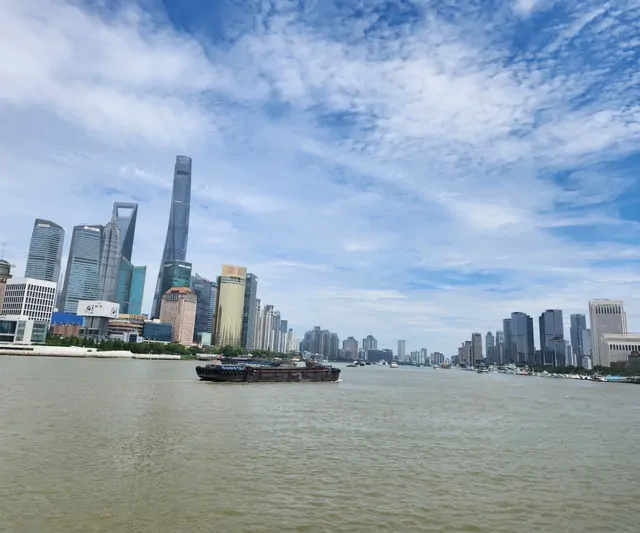 A barge crossing the Huangpu River with the Pudong skyline in the background.