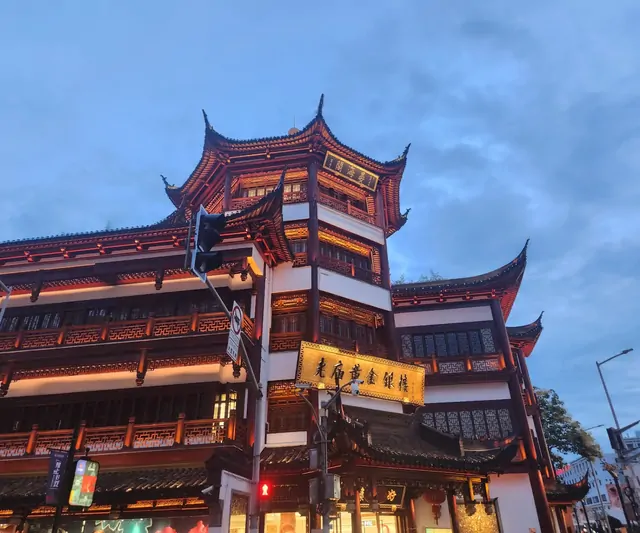Traditional Chinese pavilions illuminated by evening lights near Yu Garden.