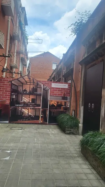 A small house-shaped sculpture nestled between red brick walls.