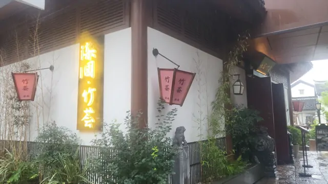 Glowing Japanese-style signs reflecting in the rain outside a restaurant.