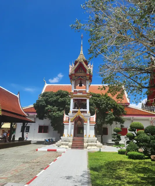 Red roofs and golden spires of a Thai temple under a clear sky.