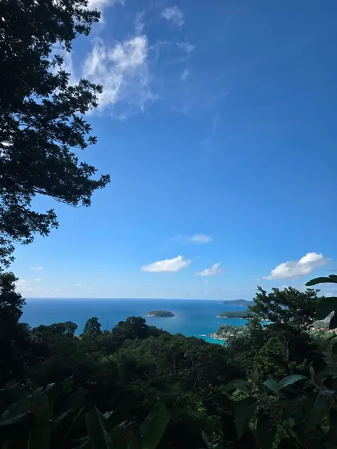 Small islands and emerald waters viewed through tropical trees.