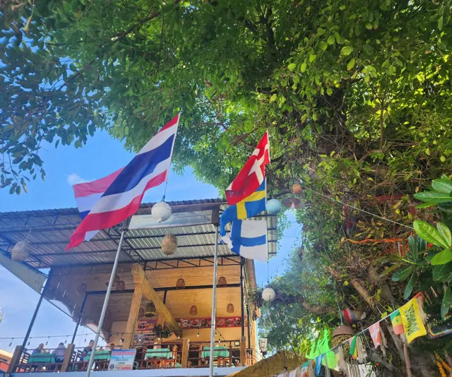 Thai and Nordic flags fluttering at an outdoor cafe terrace.